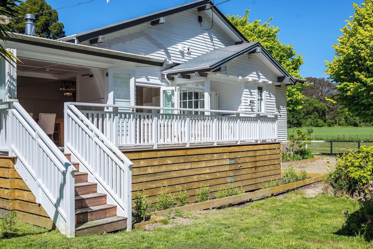 Uma casa de dois andares com um deck de madeira e um cercado branco.