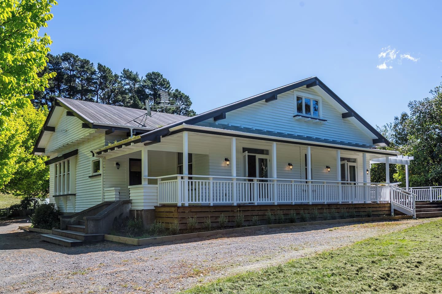 A two-story house with a porch, a satellite dish, and a gravel driveway.