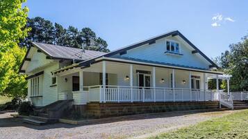 A two-story house with a porch, a satellite dish, and a gravel driveway.