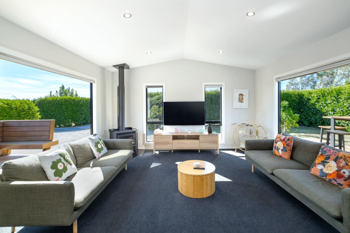 A spacious living room with a fireplace, a flat-screen TV, and a large window offering a view of the outdoors.