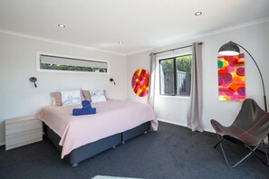A modern bedroom with a bed, a chair, a window, and artwork on the walls. - La Maison Noir, Martinborough (Martinborough)
