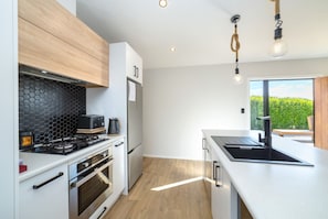 A modern kitchen with a gas stove, oven, and a built-in microwave. - La Maison Noir, Martinborough (Martinborough)