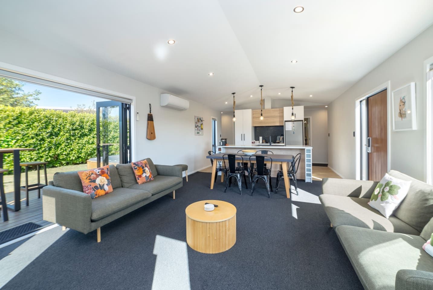 A modern living room with a sofa, a coffee table, and a dining area with chairs.