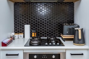 A compact kitchen with a gas stove, a coffee maker, and a kettle. - La Maison Noir, Martinborough (Martinborough)