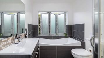 A modern bathroom with a freestanding bathtub, a large mirror, and a toilet.