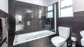 A modern bathroom with a glass-enclosed shower, a white toilet, and a bathtub.