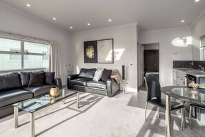 A modern living room with a sofa, coffee table, and a dining area with a glass table.