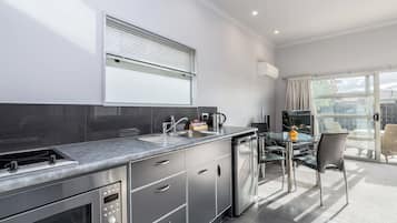 A modern kitchen with a built-in stove, sink, and a dining area with a glass table and chairs.