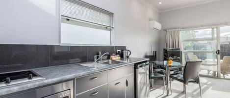 Una cocina moderna con horno integrado, lavaplatos y comedor con mesa y sillas de vidrio.