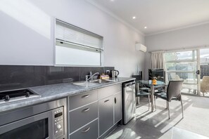 Una cocina moderna con horno integrado, lavaplatos y comedor con mesa y sillas de vidrio.