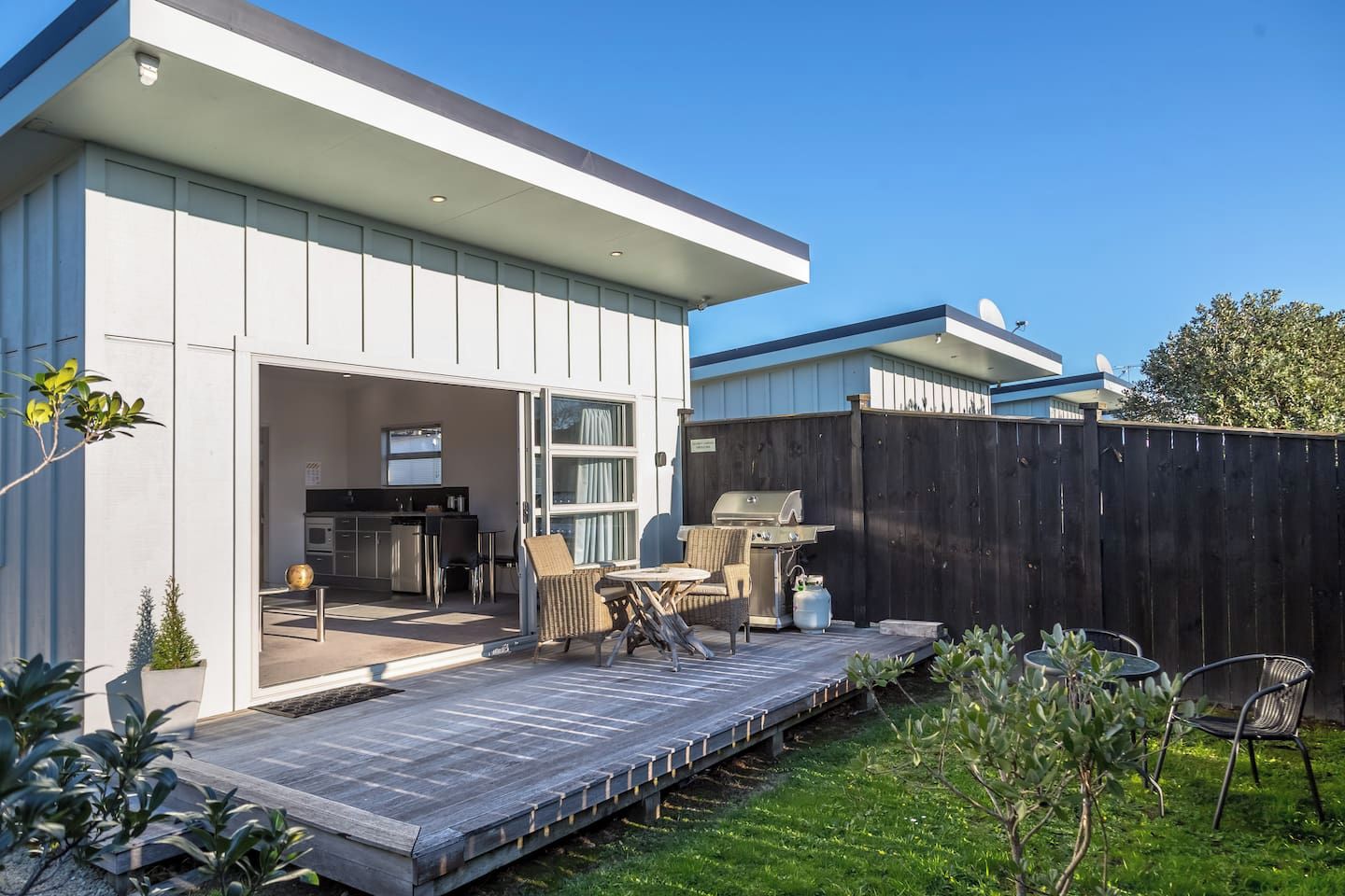 A modern house with a patio, outdoor seating, and a barbecue area.