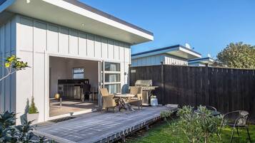 A modern house with a patio, outdoor seating, and a barbecue area.