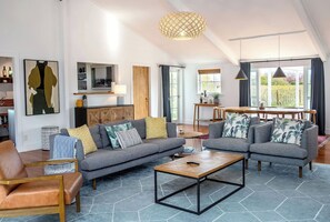 A modern living room with a grey sofa set, a wooden coffee table, and a dining area with a table and chairs.