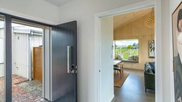 A modern interior with a dark door, a view of a patio, and a seating area with a table and chairs.