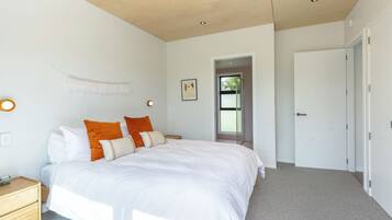 A bedroom with a bed, bedside tables, a door, and a window.