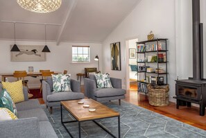 A spacious living room with a fireplace, grey sofas, a coffee table, and a bookshelf.