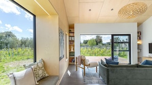 A modern living room with a large window, a sofa, a chair, and a bookshelf.