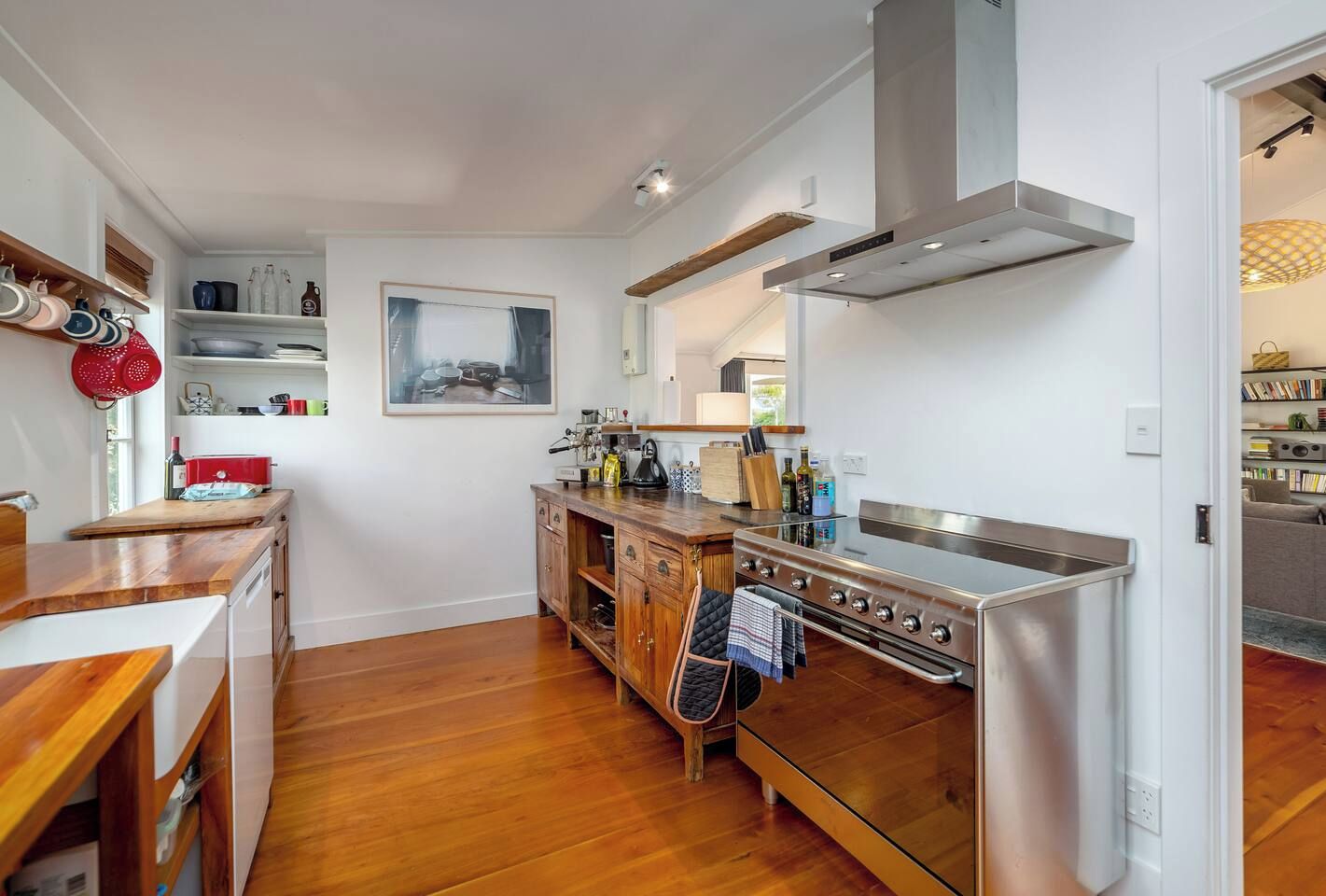 Une cuisine compacte avec des meubles en bois, une cuisinière en acier inoxydable et un porte-casseroles suspendu.