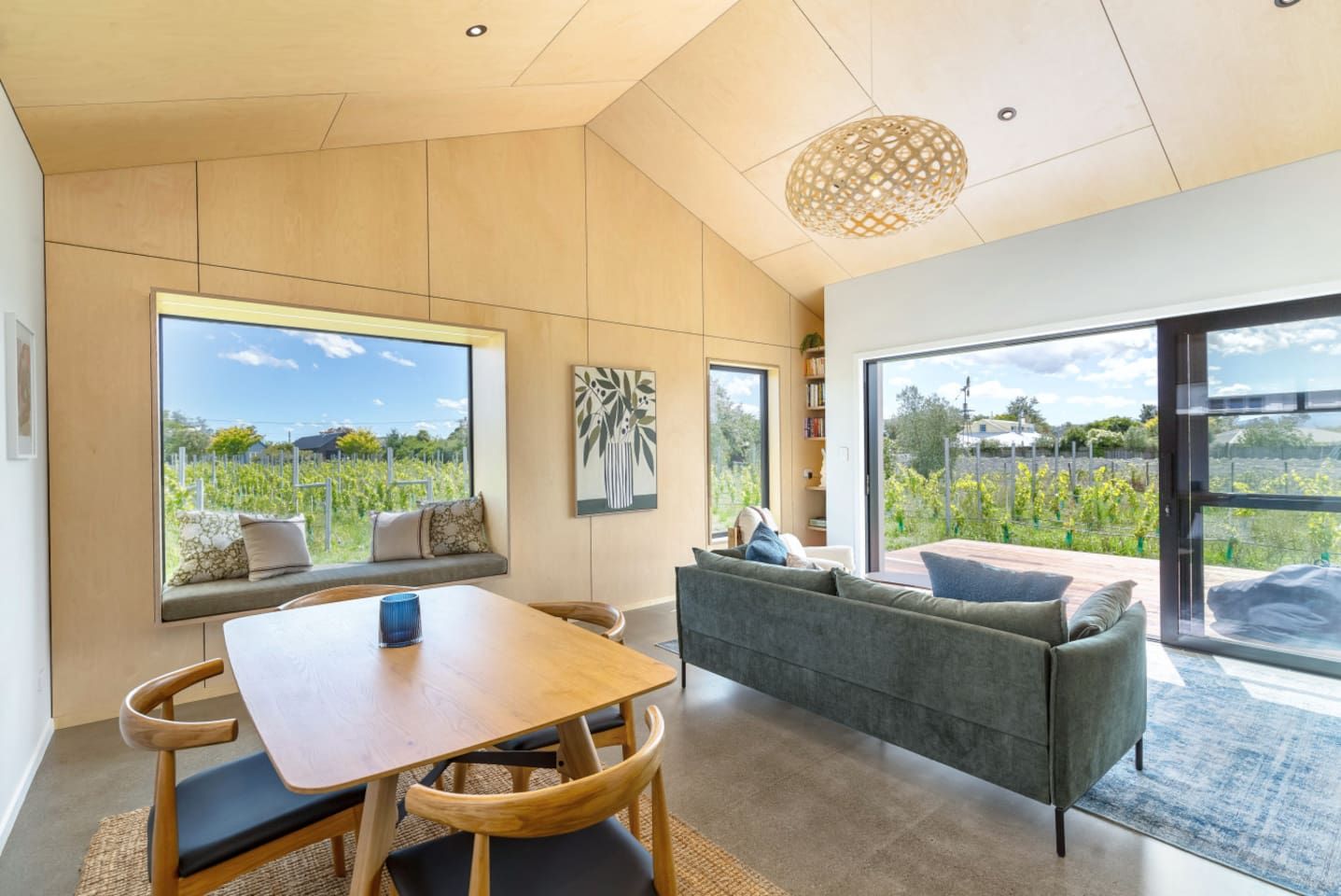 Un intérieur moderne comprenant une table à manger, un canapé et de grandes fenêtres donnant sur un jardin.