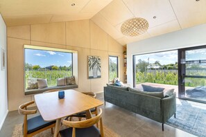 Un intérieur moderne comprenant une table à manger, un canapé et de grandes fenêtres donnant sur un jardin.