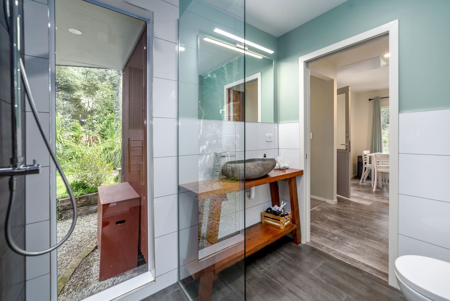 Une salle de bain moderne avec une douche à parois de verre, un meuble-lavabo en bois et un grand miroir.