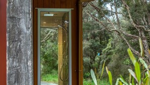 A glass door leading to a shower area with a view of a forested landscape. - The Glade, Martinborough (Ruakōkoputuna)