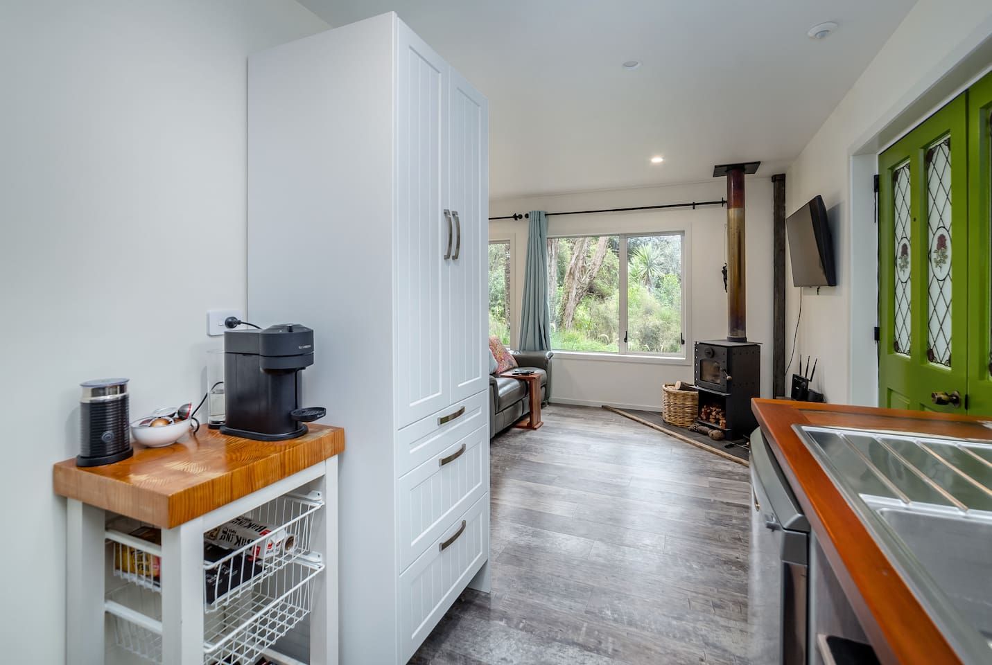A modern kitchen with a coffee machine, a built-in oven, and a large window offering a view of the outdoors.