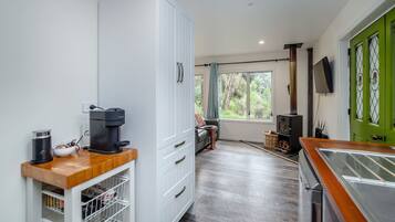 A modern kitchen with a coffee machine, a built-in oven, and a large window offering a view of the outdoors.