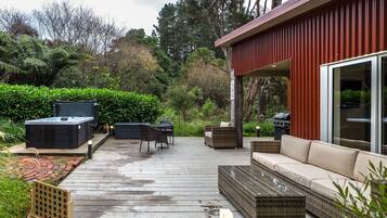 Una terraza con mobiliario exterior, un jacuzzi y una zona de parrillada.