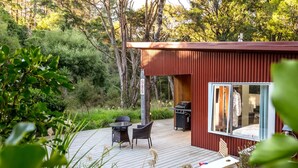 A modern outdoor deck with a grill, seating area, and a glass-enclosed room. - The  Glade, Martinborough (Ruakōkoputuna)