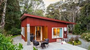 A compact cabin with a deck, a grill, and a dining area. - The  Glade, Martinborough (Ruakōkoputuna)