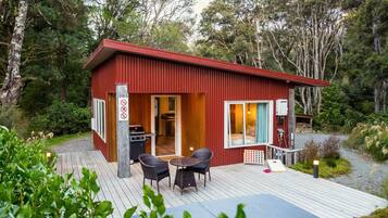 A compact cabin with a deck, a grill, and a dining area.