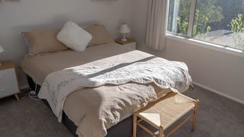 A bedroom with a bed, bedside tables, a bench, and a window with a view.