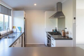 Une cuisine moderne équipée d’appareils électroménagers en acier inoxydable, d’une cuisinière à gaz et d’une hotte aspirante.