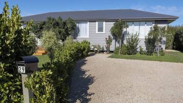 A residential house with a gravel driveway, a mailbox, and a well-maintained lawn.