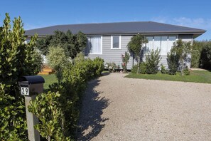 Une maison d’habitation avec une allée en gravier, une boîte aux lettres et une pelouse bien entretenue.