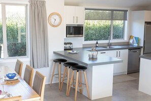 A modern kitchen with a central island, bar stools, a microwave, and a refrigerator.