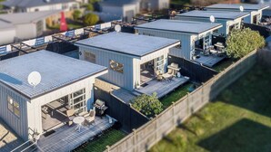 Een woonwijk met meerdere moderne huizen, elk voorzien van schotels, tuinmeubilair en een verzorgd gazon.