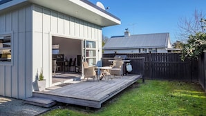 Een modern huis met een terras, zitplaatsen buiten en een barbecueplek.