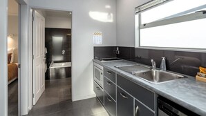 A modern kitchen with a double sink, dark cabinetry, and a window providing natural light. - TWO FOUR COLOGNE #4, Martinborough (Martinborough)