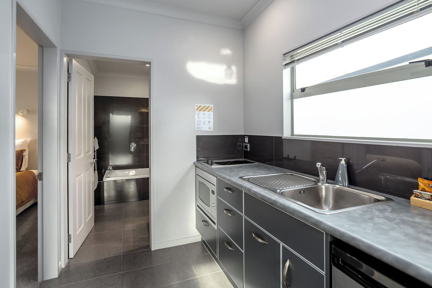 A modern kitchen with a stainless steel sink, a dishwasher, and a window above the sink.