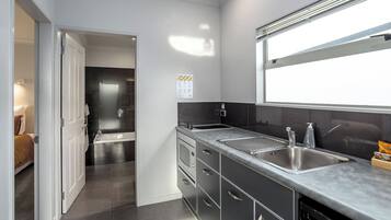 A modern kitchen with a stainless steel sink, a dishwasher, and a window above the sink.