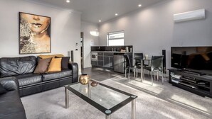 A modern living room with a black leather sofa, a glass coffee table, and a large flat-screen TV. - TWO FOUR COLOGNE #4, Martinborough (Martinborough)