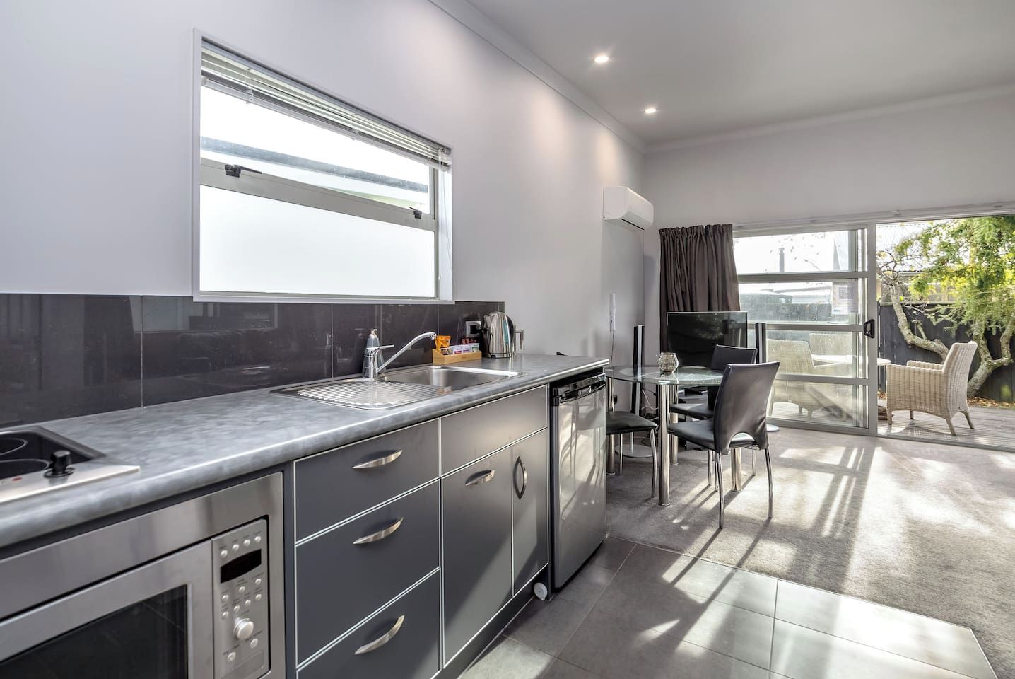 A modern kitchen with a built-in oven, a sink, and a dining area with a table and chairs.