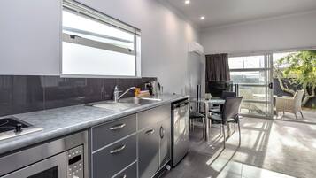 A modern kitchen with a built-in oven, a sink, and a dining area with a table and chairs.