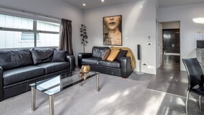 A modern living room with two black leather sofas, a glass coffee table, and a large abstract painting on the wall. - TWO FOUR COLOGNE #4, Martinborough (Martinborough)