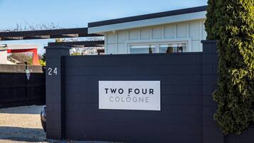 A black gate with a sign that reads 'TWO FOUR COLOGNE' and the number '24' on it.