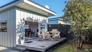 Een modern huis met een terras, zitplaatsen buiten en een barbecueplek.