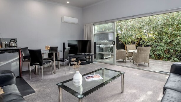 Een moderne woonkamer met een glazen salontafel, een leren bank in zwart leer en een televisie.