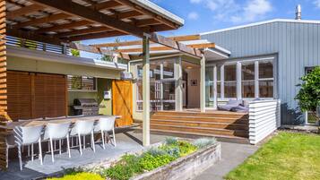 Une maison moderne dotée d’un patio, d’un espace salon extérieur et d’une zone couverte.